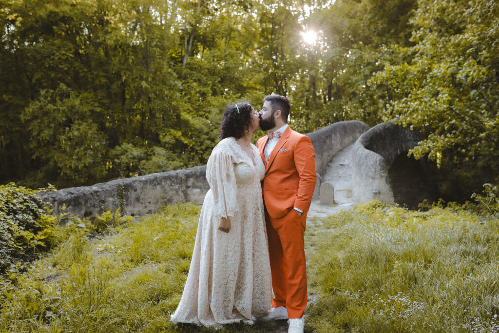 Couple de jeunes mariés qui s'embrassent devant un pont