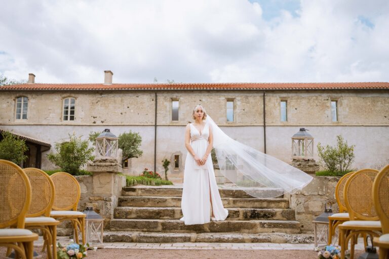 mariée en haut d'escalier avec le vent qui soulève son voile