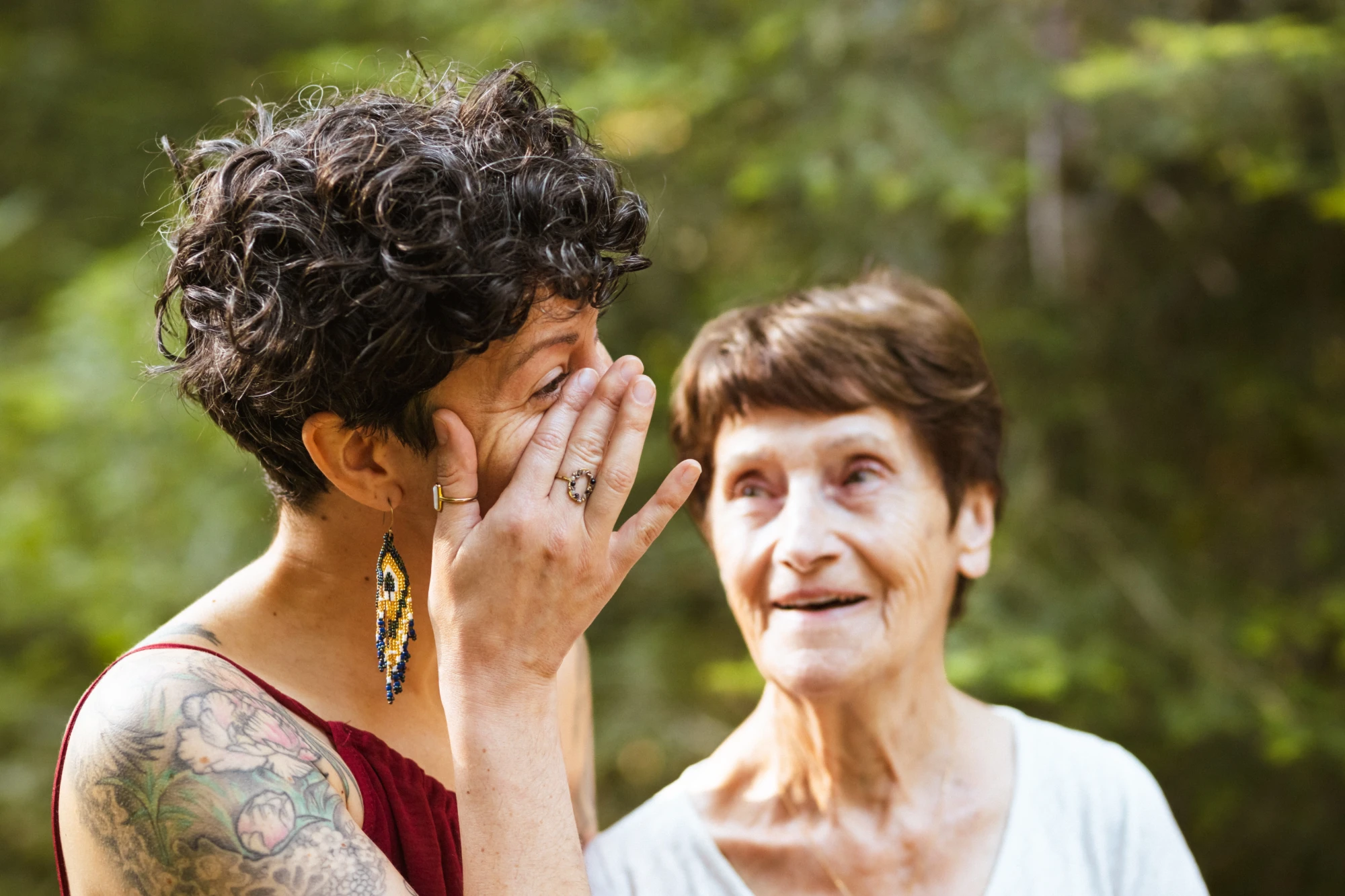 Une petite-fille essuie une larme pendant que sa grand-mère la regarde en souriant
