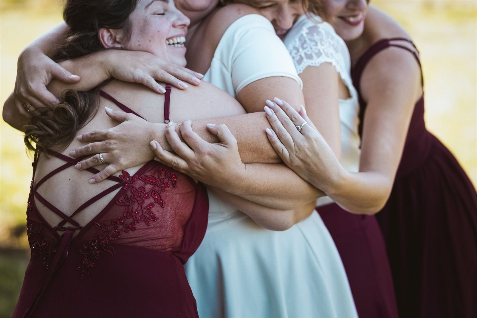 La mariée et ses amies en robes bordeaux s'enlacent en riant, photographe de mariage à Clermont-Ferrand