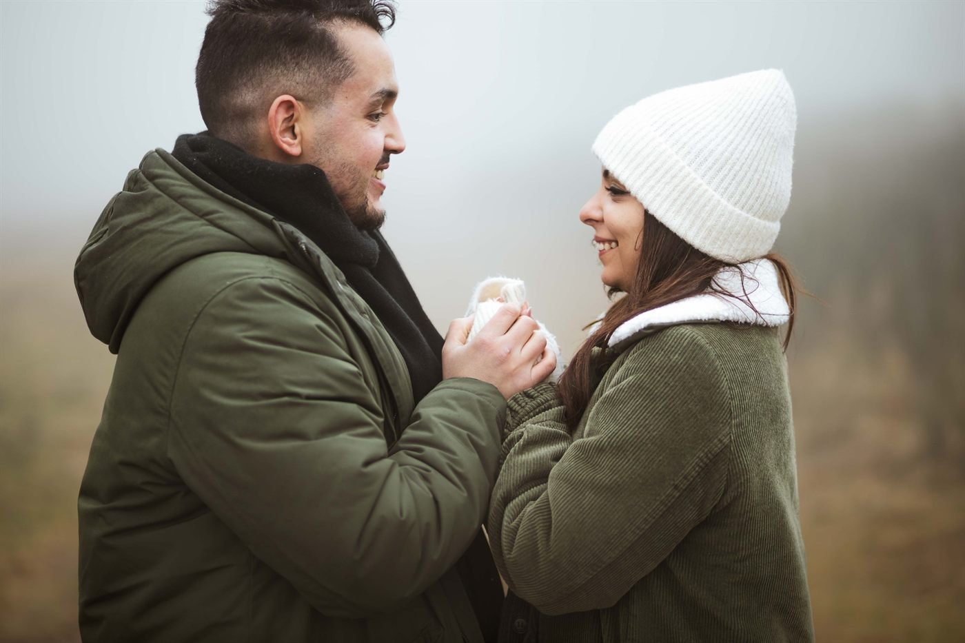 Fiancés qui se tiennent les mains et se sourient pendant une séance photo couple